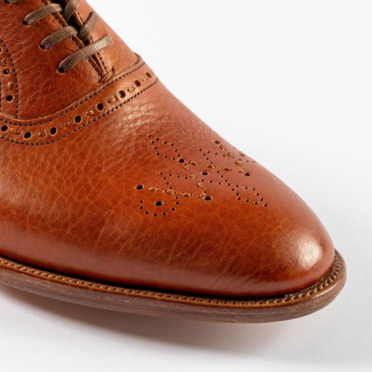 Closeup of signature E.Woodford medallion on Redbourne Oxford in Tan Horween Veg Tanned Bison